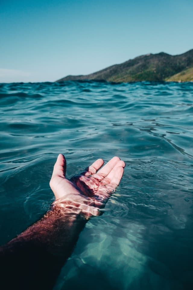 Image of a hand held out on the surface of the water.